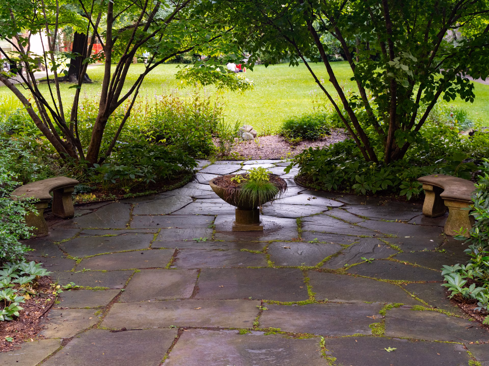 Shaded flagstone patio surrounded by lush garden beds