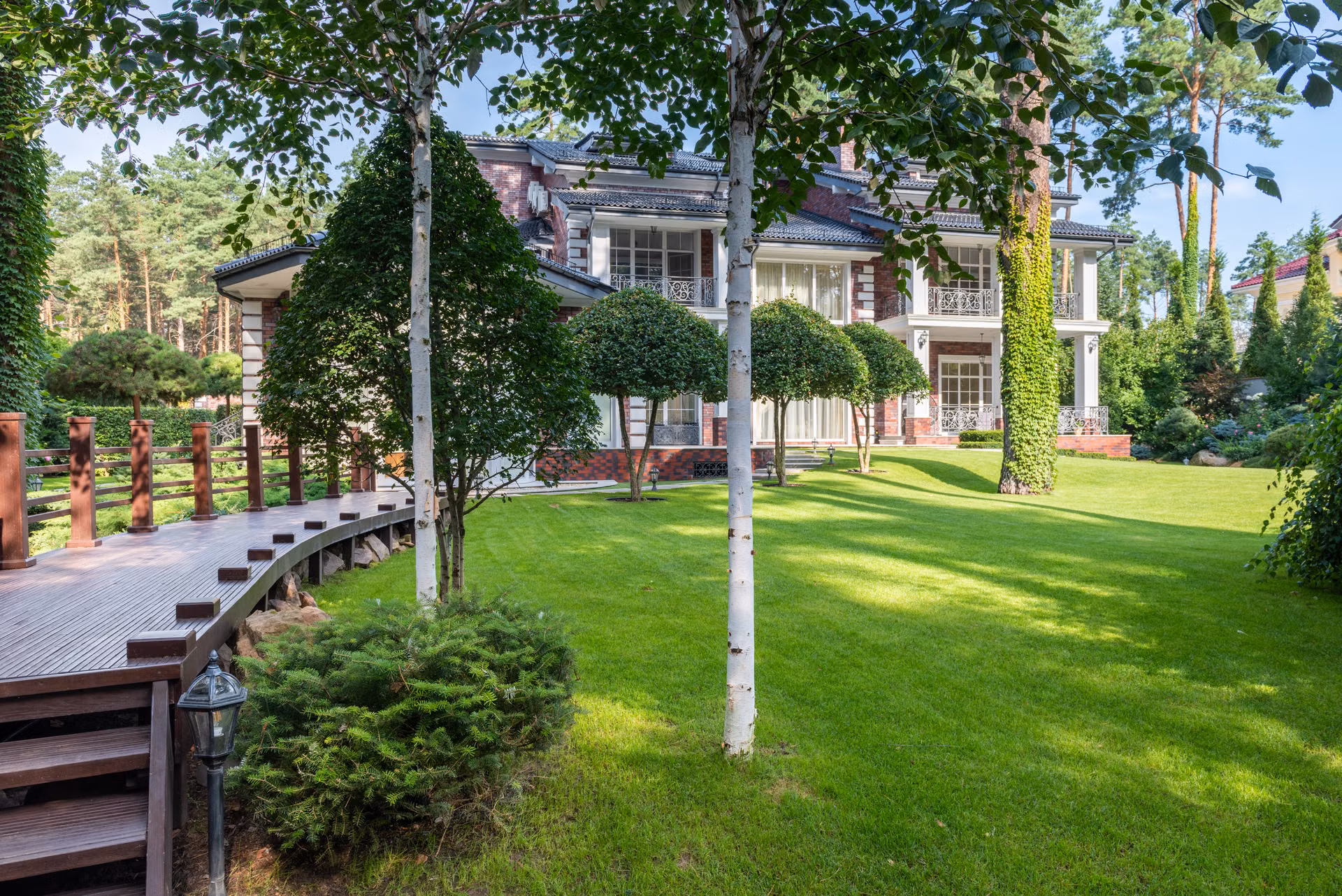 Sweeping green lawn with mature trees in front of a large home